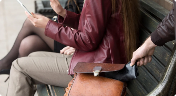 Pickpocket taking a wallet from a bag on a bench